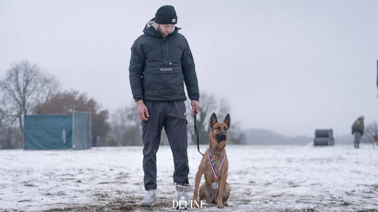 Jason and his Malinois standing together on a snow-covered trial field